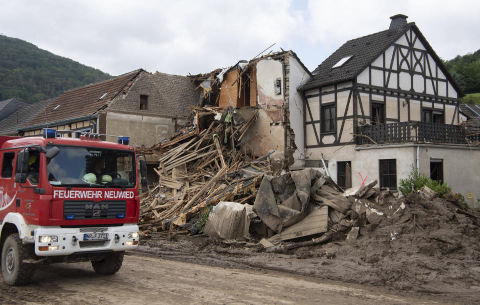 Firefighters stand in front of a destroyed house in Altenahr, Germany, Monday, July 19, 2021. Numerous houses in the town were completely destroyed or severely damaged, there are numerous fatalities. (Boris Roessler/dpa via AP)