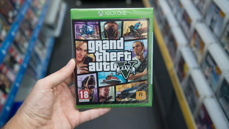 Man holding Grand Theft Auto 5 videogame on Microsoft XBOX One c