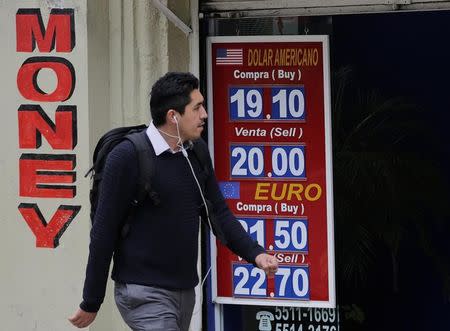 A man walks past a board displaying the exchange rates of Mexican peso against the U.S. dollar and the Euro at a foreign exchange house in Mexico City, Mexico November 17, 2016. REUTERS/Henry Romero