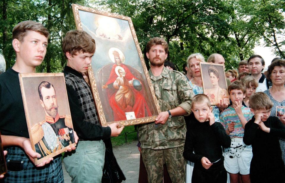 Royalist supporters stand in the street with portaits of the last Russian Tzar Nicholas II and his wife Alexandra during the burial ceremony of the Tzar's family remains in 1998.