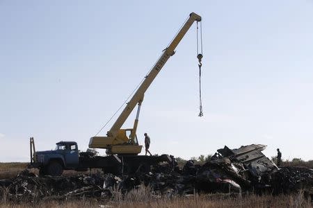 Members of the Ukrainian Emergencies Ministry and a crane operator work at the crash site of Malaysia Airlines Flight MH17, near the village of Hrabove, Donetsk region, July 20, 2014. REUTERS/Maxim Zmeyev