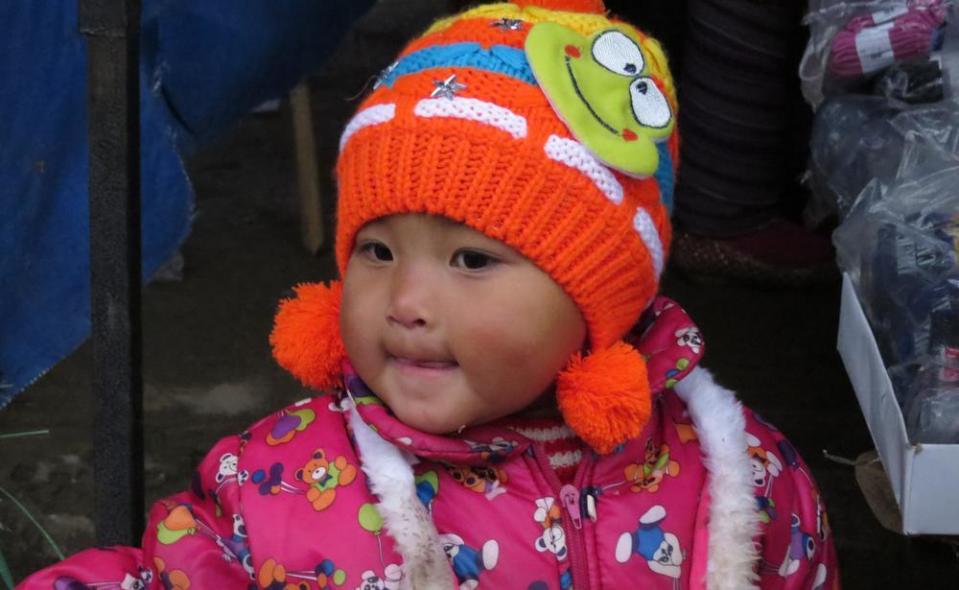 A happy baby shopper rug up in colourful, warm garb.