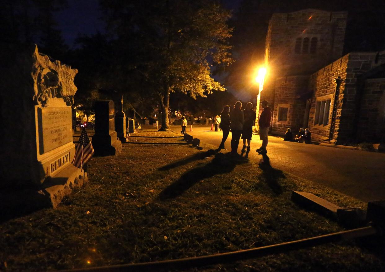 People gather in front of the chapel/office as they wait for a nighttime lantern tour called "Murder and Mayhem" to begin at the Sleepy Hollow Cemetery.