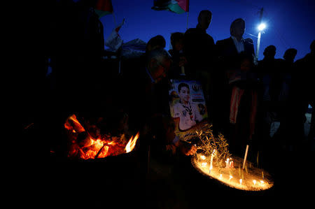 A man lights candles on a tire during a symbolic birthday party for Palestinian boy Hussein Madi, who was killed at the Israel-Gaza border, at a tent city protest east of Gaza City April 9, 2018. REUTERS/Mohammed Salem