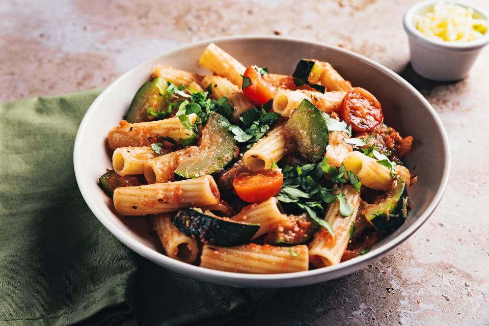 Wholewheat pasta with tomatoes, courgettes, and other vegetables in a bowl.