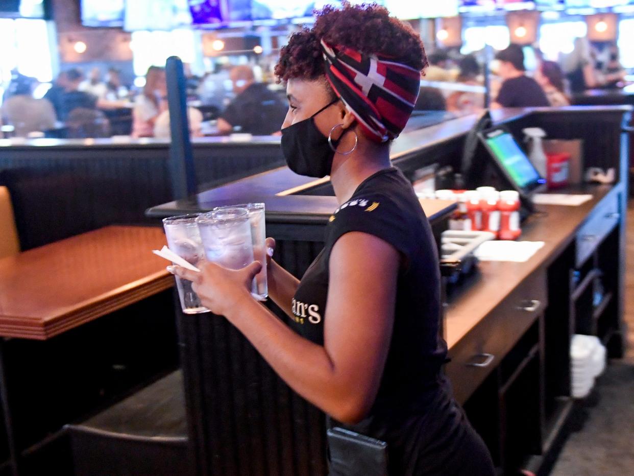 A server carries drinks to a table at P.J. Whelihan's restaurant and pub in Spring Township