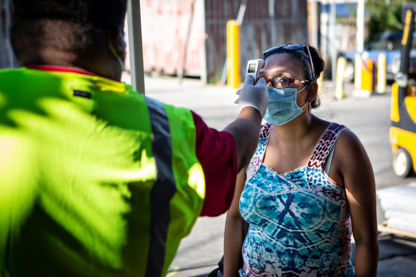 LOS ANGELES, CA - JULY 15: An employee of LA Apparel has her temperature checked before entering LA Apparel for a health and safety training session on Wednesday, July 15, 2020 in Los Angeles, CA. The clothing factory was shutdown by city officials due to a huge coronavirus outbreak. (Jason Armond / Los Angeles Times)