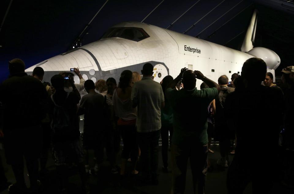 Visitors look at the space shuttle Enterprise in its newly completed pavilion on the deck of the Intrepid Sea, Air & Space Museum in New York, Wednesday, July 10, 2013. With a ribbon-cutting ceremony the pioneering shuttle has been restored from the damages it incurred during Superstorm Sandy. (AP Photo/Seth Wenig)