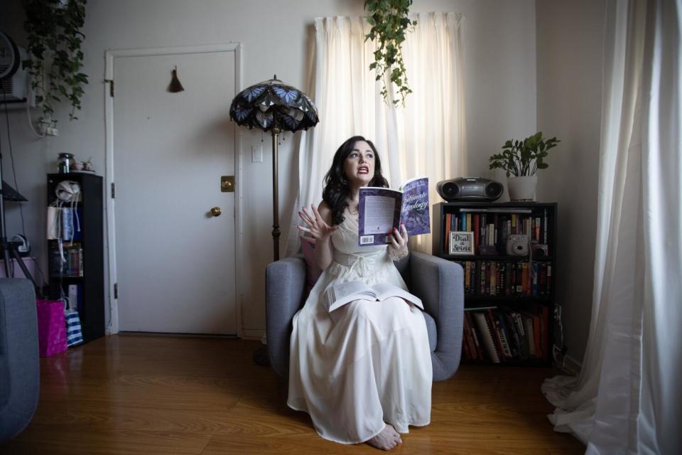 Gogo Akopyan sits next to a small bookcase in a room and reads a book.