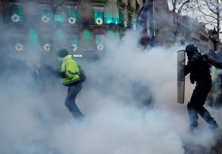 A protester wearing a yellow vest runs as French police fire tear gas during a demonstration of the "yellow vests" movement in Paris, France, December 15, 2018. REUTERS/Gonzalo Fuentes