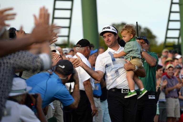 Bubba Watson of the US carries his son Caleb as he greets the crowd after putting on the 18th green during the 78th Masters Golf Tournament, at Augusta National Golf Club in Georgia, on April 13, 2014