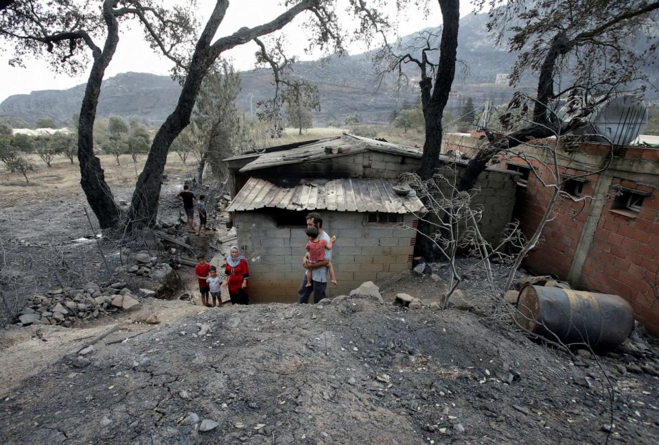 PHOTO: Amar Belkati, a 57-year-old farmer, walks with his family outside their burnt house following a wildfire in Bejaia, Algeria, on July 25, 2023. (Ramzi Boudina/Reuters)