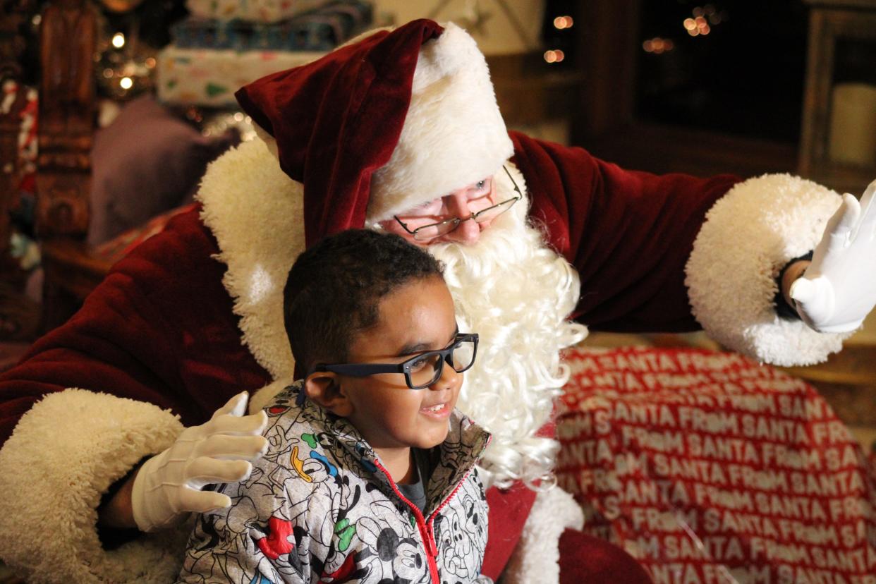 Santa Claus poses for a photo with children at the Olsen Christmas Wish gift giving event.