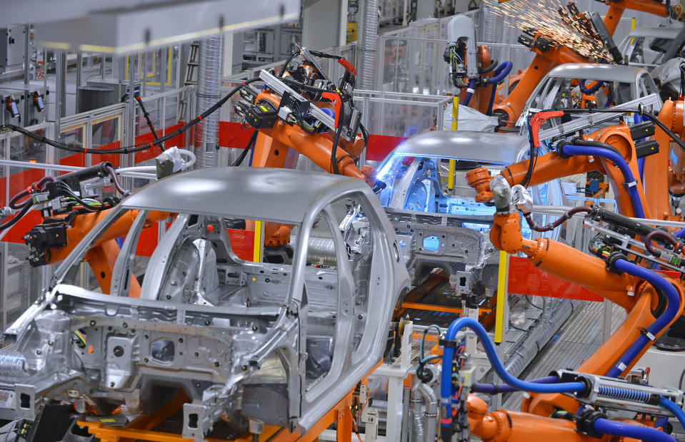 Robotic arms assembling cars in a factory.