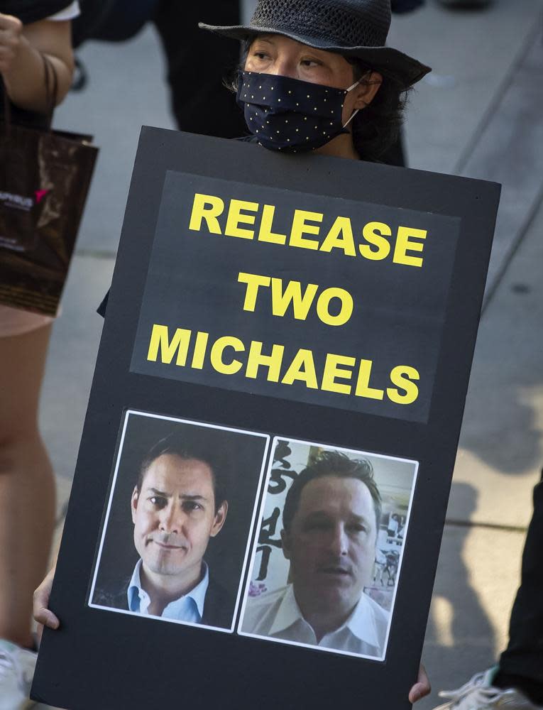 A woman holds a sign with images of Michael Kovrig, left, and Michael Spavor, who have been detained in China since December 2018, during a rally in support of Hong Kong democracy in Vancouver, Canada.