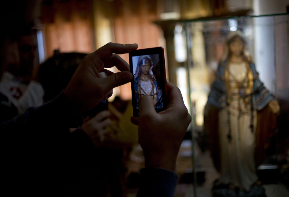 A Christian worshiper uses a mobile phone to take a photograph of a statue of the Virgin Mary, that residents say "weeps" oil, in an apartment belonging to the Khoury family, in Tarshiha, a small Israeli town near the Lebanon border, Tuesday, Feb. 11, 2014. The family says it is most striking when a "tear" seems to roll down the statue's cheek. Parts of the statue appear to be slick with moisture, even after it is wiped off. (AP Photo/Ariel Schalit)