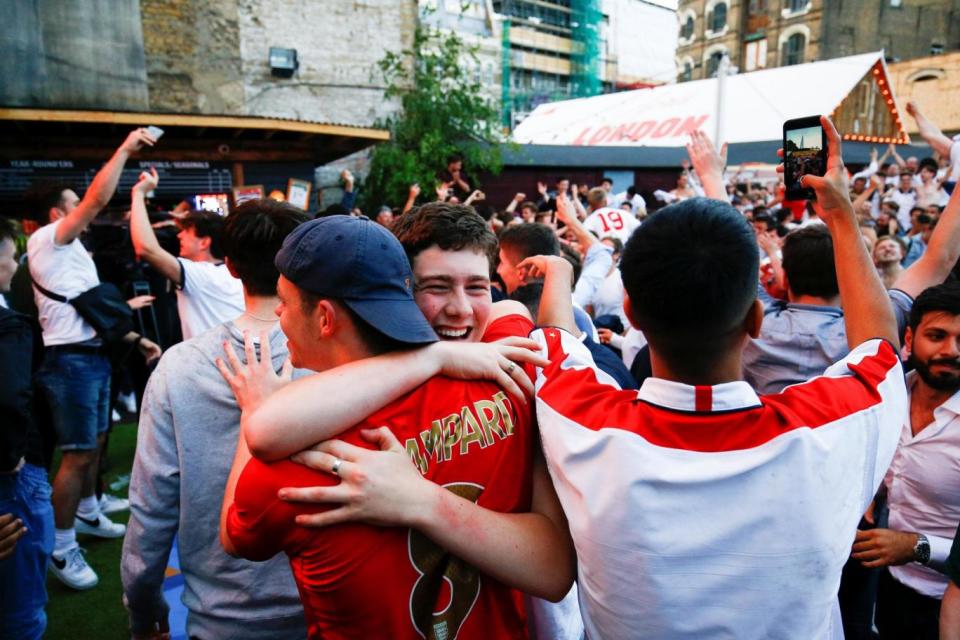 Fans in London turn to hug each other as they celebrate during the match (REUTERS)