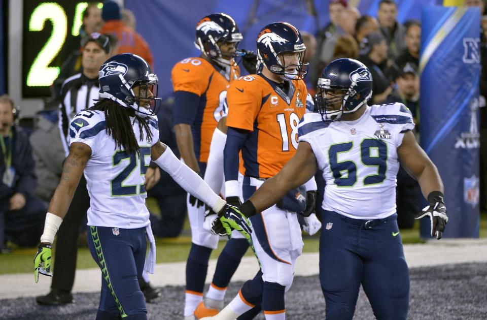 Seattle Seahawks' Richard Sherman, left, and Clinton McDonald, right, react in front of Denver Broncos' Peyton Manning (18) after a safety during the first half of the NFL Super Bowl XLVIII football game Sunday, Feb. 2, 2014, in East Rutherford, N.J. (AP Photo/Bill Kostroun)