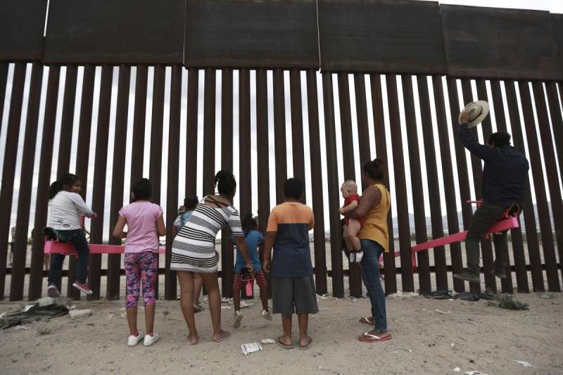 兩位教授在美墨邊境高牆設立「邊境翹翹板」，兩邊的大人小ˋ孩玩得不亦樂乎。（AP）