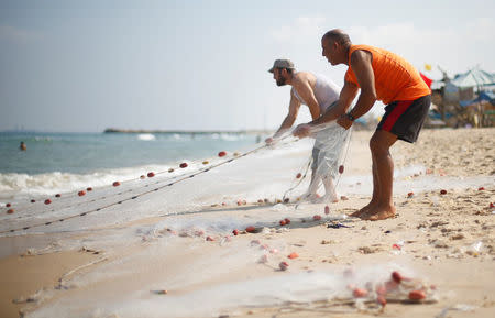 Palestinian fisherman Jihad al-Soltan (R) pulls his fishing net on a beach in the northern Gaza Strip August 21, 2017. REUTERS/Mohammed Salem