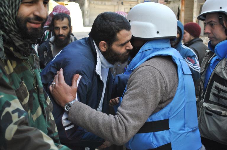 Members of a United Nations and Syria's Red Crescent convoy are welcomed by rebel fighters after entering a besieged district of Homs, on February 8, 2014