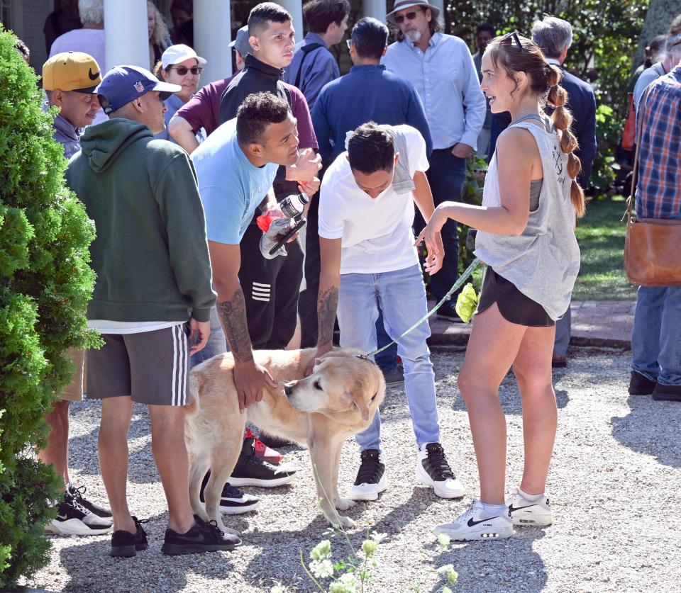 Bella Carillo of Edgartown of Sandy Tails Pet Sitting offered Gracie, her charge for the day, to migrant visitors in front of St. Andrews Parish Hall in Edgartown Thursday morning. Her father was from Venezuela and she spoke some Spanish, Carillo said.