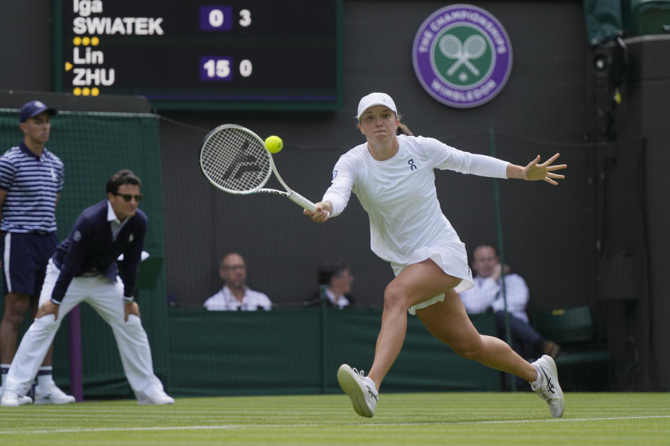 Iga Swiatek devuelve ante Zhu Lin durante la primera ronda del torneo de Wimbledon, el lunes 3 de julio de 2023, en Londres. (AP Foto/Alastair Grant)