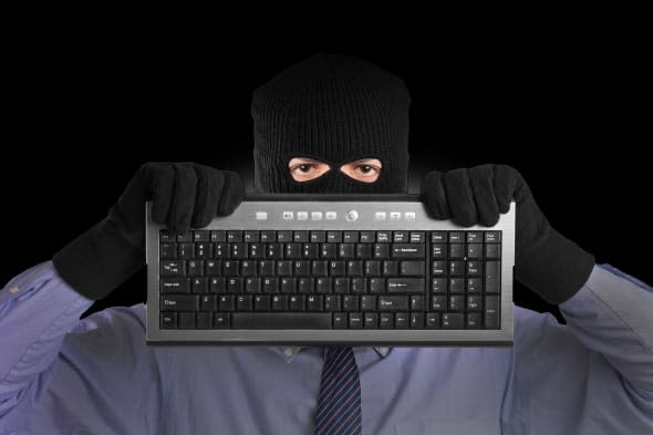 BYRP3Y A hacker with robbery mask holding a keyboard scam email scammer scammed computer scam adult; background; bandit; black;