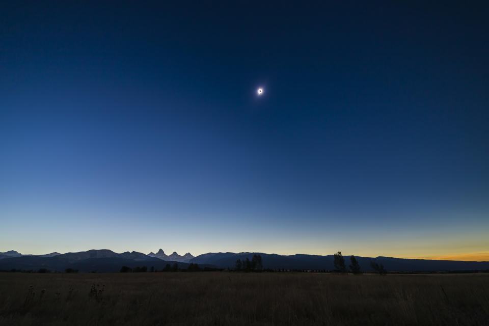 the sky appears dark blue during an eclipse over a distant mountain range