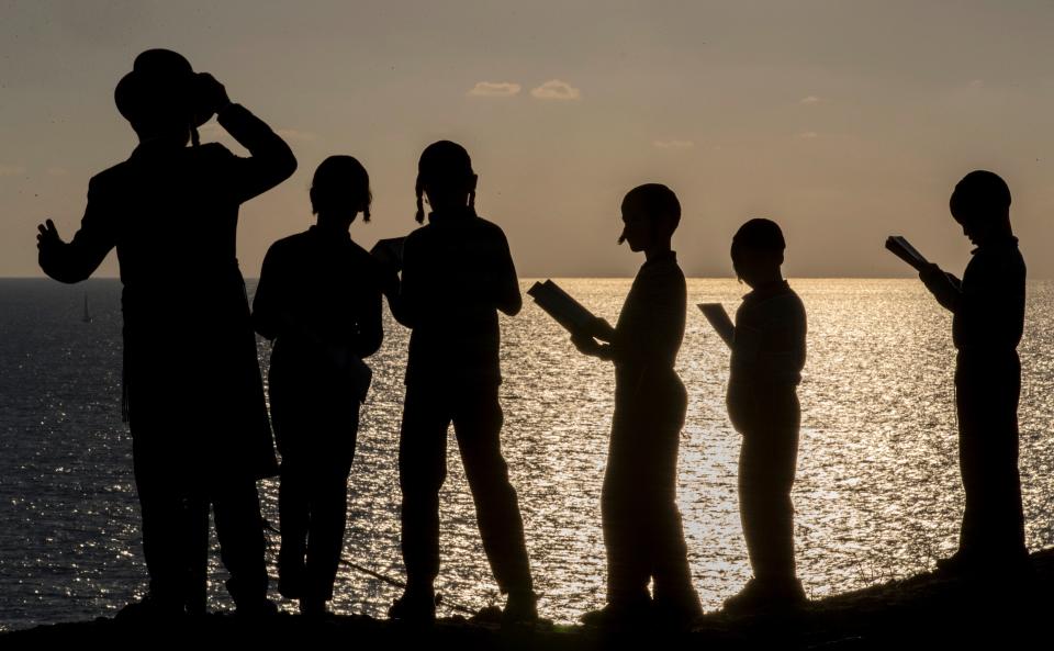 Boys pray along the Mediterranean Sea