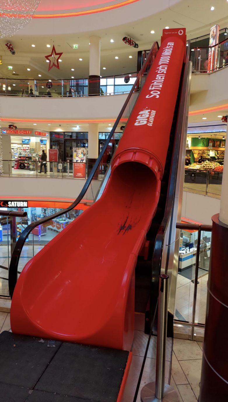 A large red indoor slide with a sign that says "MAGIC SLIDE" at a shopping mall