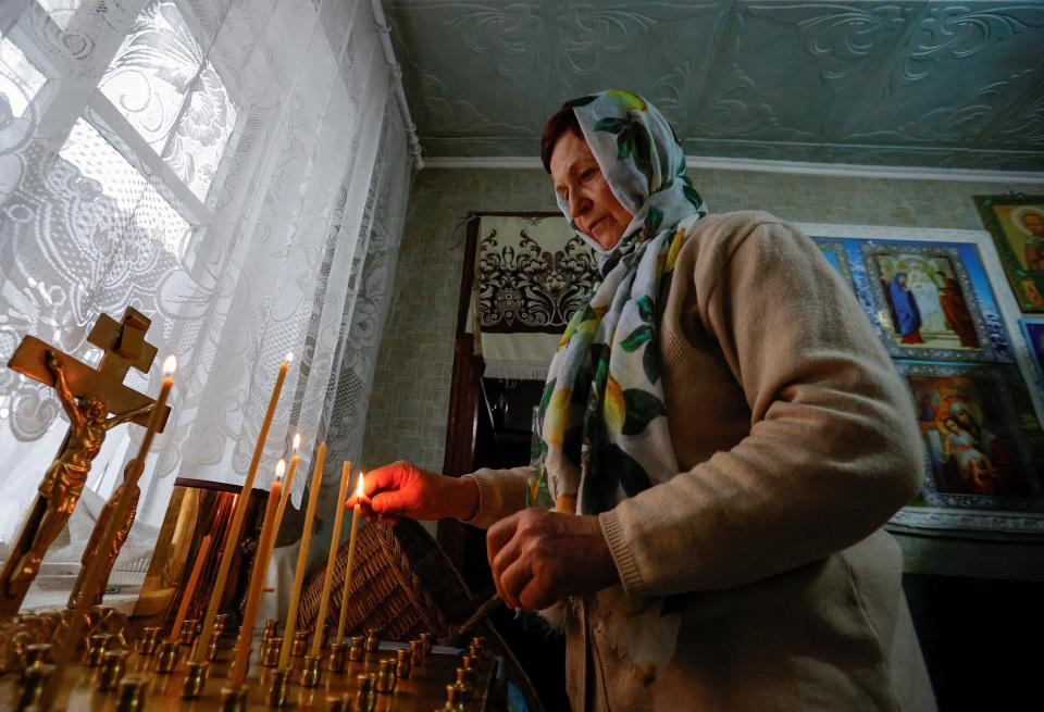 A woman lights candles at the ceremony in Volnovakha (Reuters)