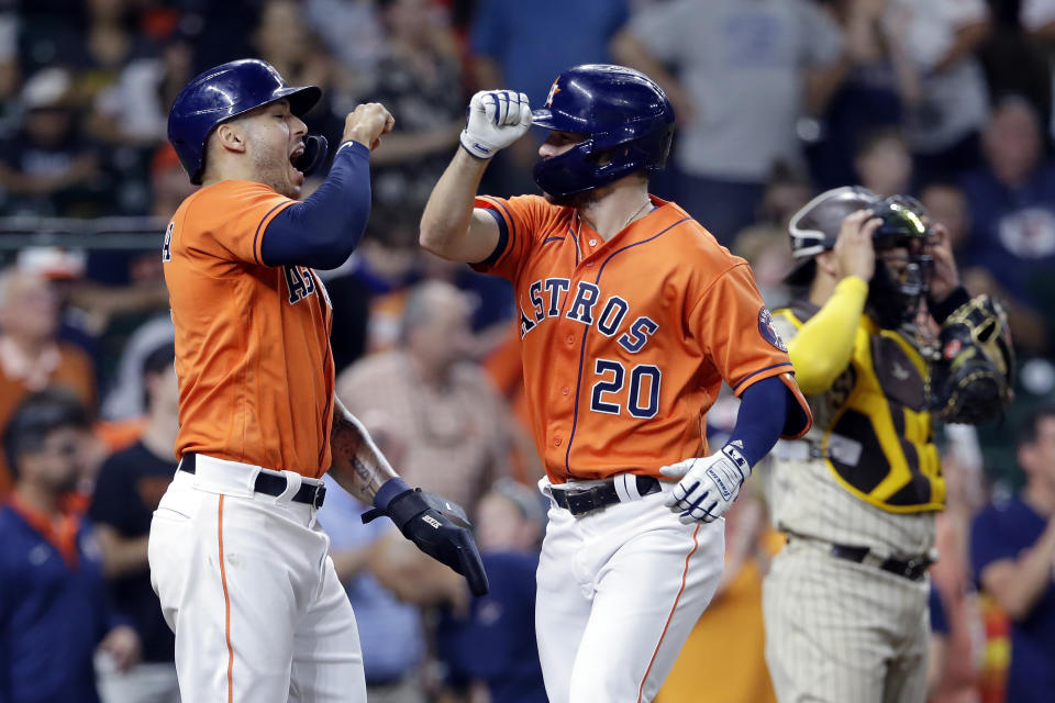Houston Astros' Carlos Correa, left, and Chas McCormick (20) celebrate next to San Diego Padres catcher Webster Rivas, right, after they both scored on a home run by McCormick during the inning of a baseball game Friday, May 28, 2021, in Houston. (AP Photo/Michael Wyke)