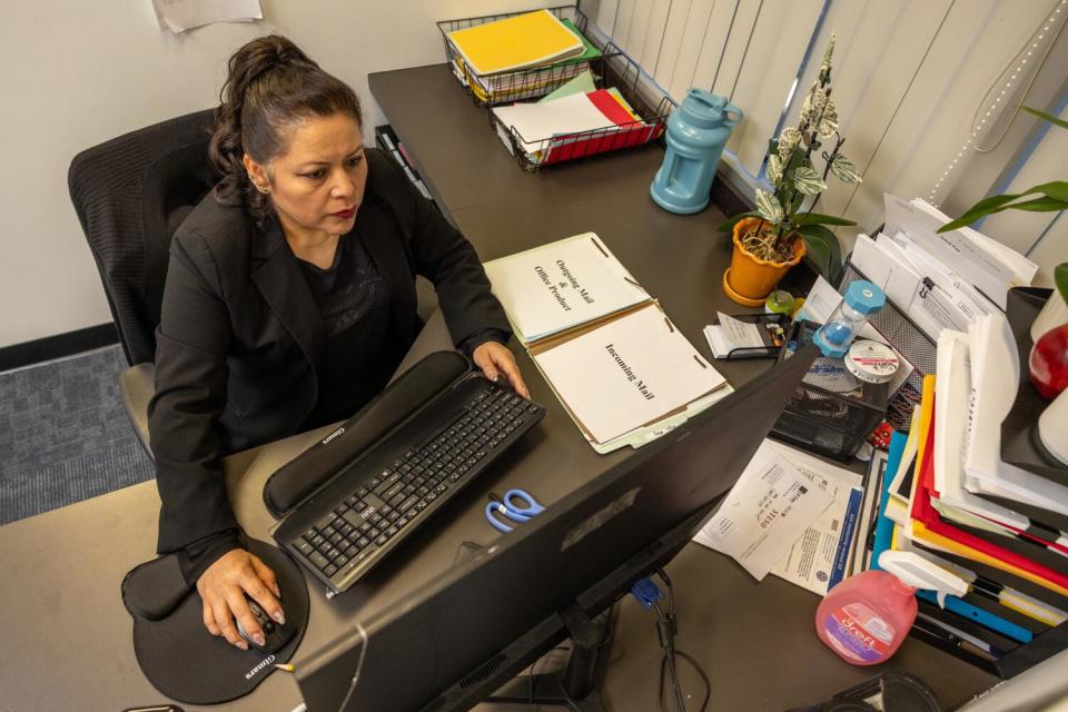 Maria Del Pilar Barradas-Medel sits at a desk using a computer in the law firm where she works.