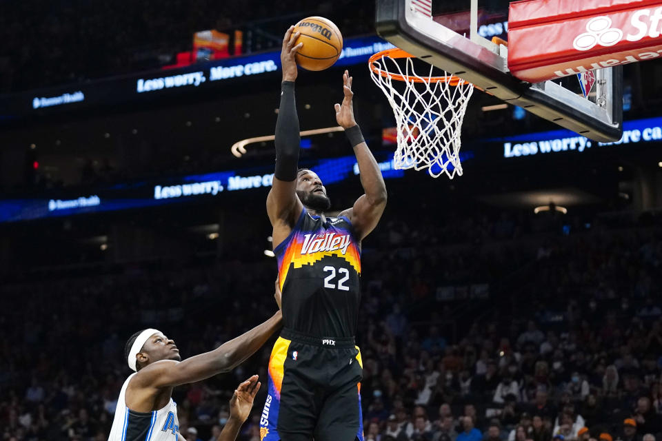 Phoenix Suns center Deandre Ayton (22) scores next to Orlando Magic center Mo Bamba during the first half of an NBA basketball game Saturday, Feb. 12, 2022, in Phoenix. (AP Photo/Ross D. Franklin)