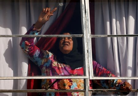 A woman points at a hole in her home window, left by a stray bullet fired during inter-gang violence in Manenberg township, Cape Town