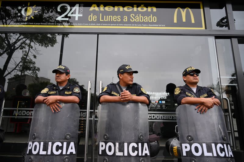 Police stand guard outside a closed McDonald's restaurant, during a protest after the deaths of two teenaged employees, in Lima