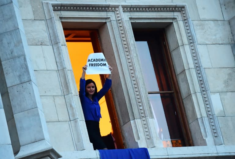 Member of Parliament Agnes Kunhalmi of the Hungarian Socialist Party displays an EU flag at the window of an office room in the parliament building as protesters gather below on April 4, 2017
