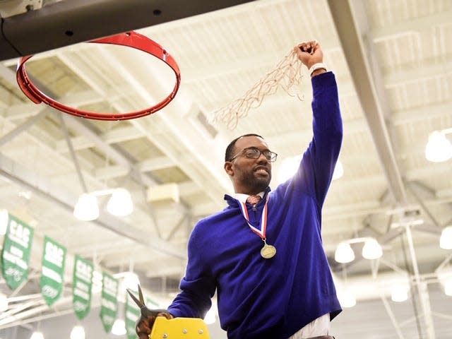 York High boys' basketball coach Clovis Gallon raises the net above his head after his team's 54-50 victory over New Oxford in the YAIAA title game at York College Friday.