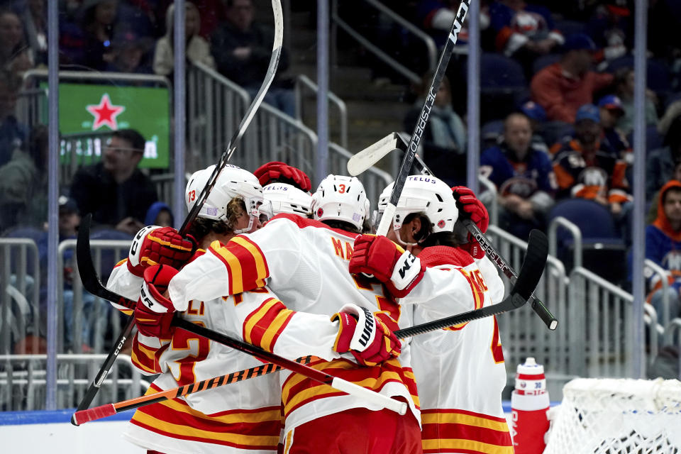Calgary Flames right wing Tyler Toffoli (73), defenseman Connor Mackey (3) and others celebrate center Mikael Backlund's (11) goal during the first period of an NHL hockey game against the New York Islanders, Monday, Nov. 7, 2022, in Elmont, N.Y. (AP Photo/Julia Nikhinson)