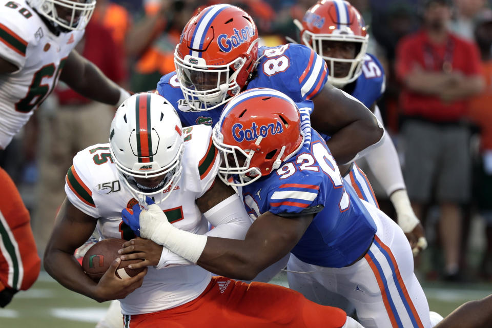 FILE - In this Aug. 24, 2019, file photo, Miami quarterback Jarren Williams, left, is sacked by defensive linemen Adam Shuler, center, and Jabari Zuniga, right, during the first half of an NCAA college football game in Orlando, Fla. This is the time of year when the Southeastern Conference usually validates its claim as the best league in college football by dominating neutral-site nonconference matchups. The SEC is 21-6 in regular-season nonconference games against Power Five opponents at neutral sites since 2012. (AP Photo/John Raoux, File)