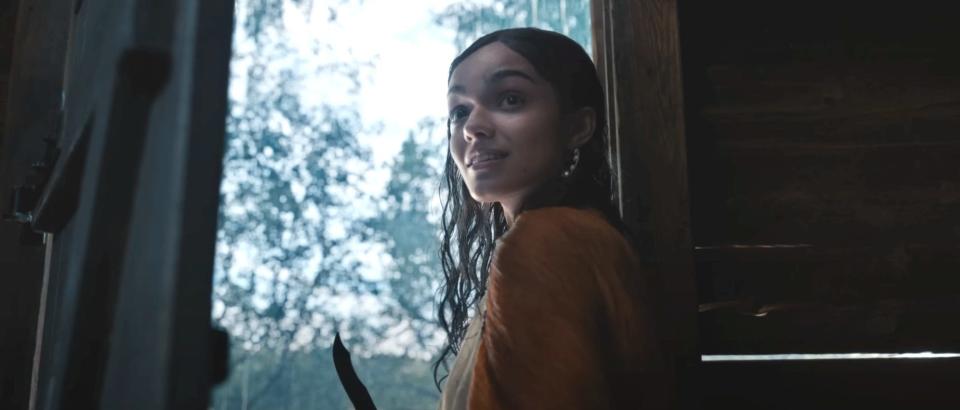 Rachel Zegler as Lucy Gray Baird stands in a doorway with wet hair and a knife in hand in "The Hunger Games" prequel.