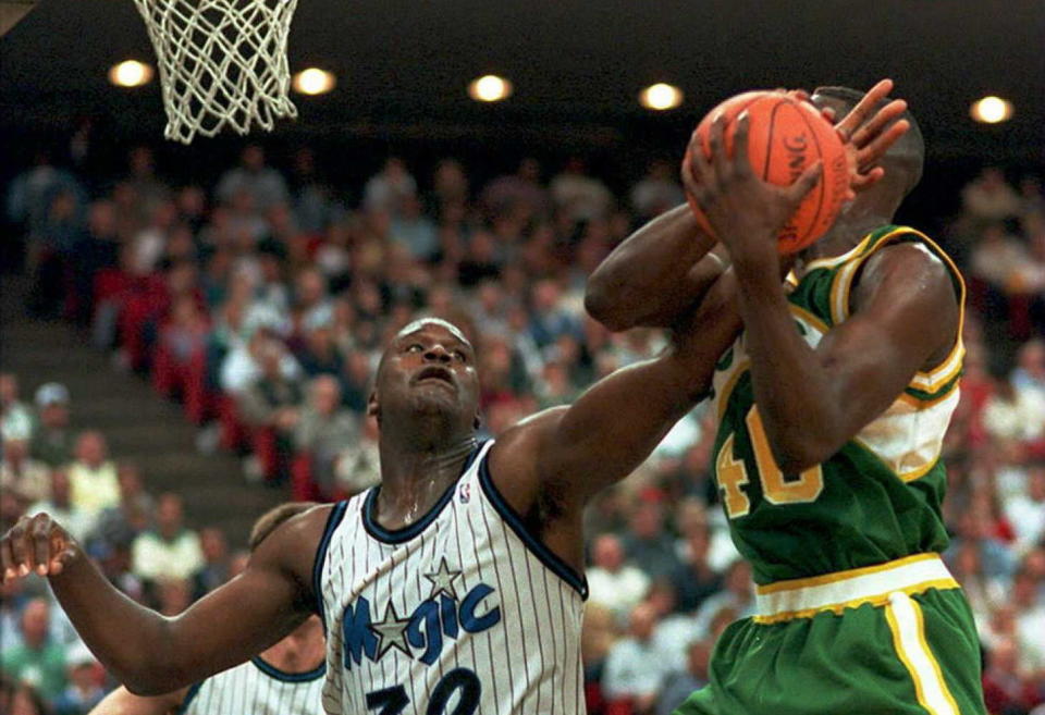 Seattle Supersonics forward Shawn Kemp drives to the basket as Shaquille O'Neal gets a hand on the ball at the Orlando Arena, FL. (DAVID MILLS/AFP/Getty Images)