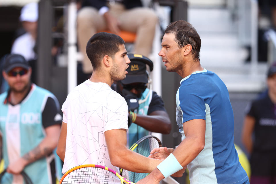 Carlos Alcaraz and Rafa Nadal embrace at the net in Monte Carlo.