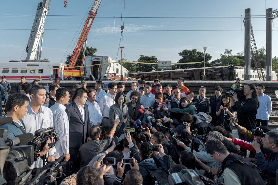 In this photo released by the Taiwan Presidential Office, Taiwanese President Tsai Ing-wen, center, briefs journalists at the site of a train derailment in Yilan county in northeastern Taiwan on Monday, Oct. 22, 2018. Passengers were killed and injured on Sunday when one of Taiwan's newer, faster trains derailed on a curve along a popular weekend route, officials said. (Taiwan Presidential Office via AP)