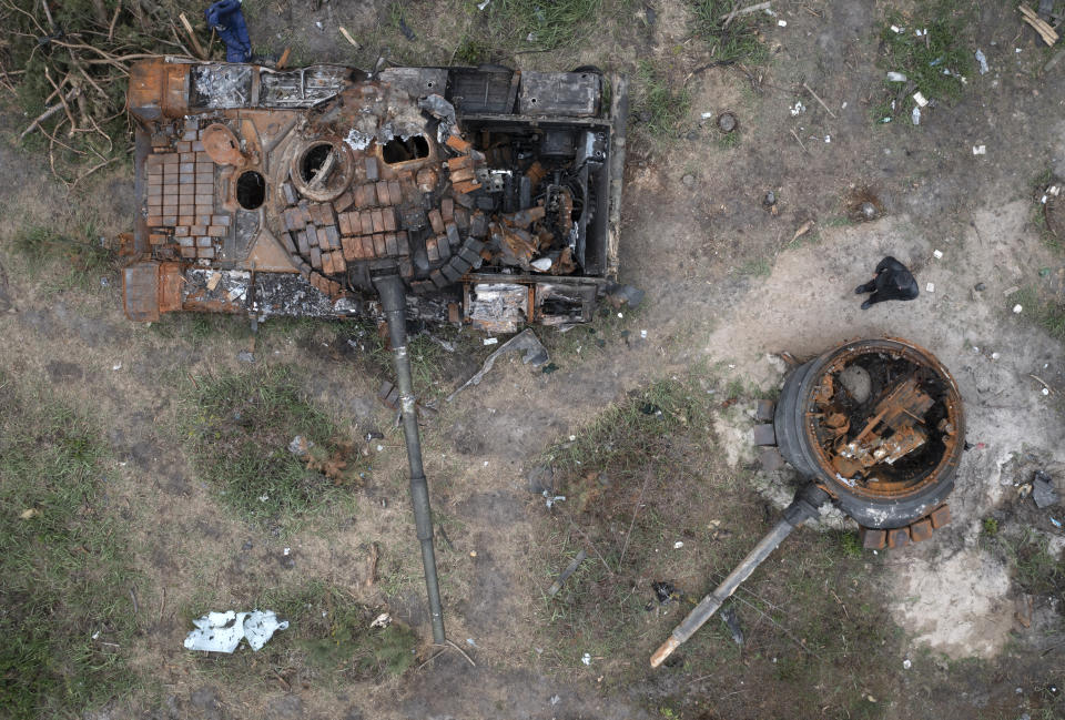 A man passes by Russian tanks destroyed in a recent battle against Ukrainians in the village of Dmytrivka, close to Kyiv, Ukraine, Monday, May 23, 2022. (AP Photo/Efrem Lukatsky)