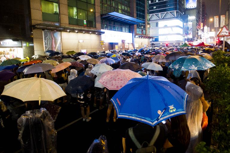 People attend a speech as the rain falls in the Mong Kok district of Hong Kong on September 30, 2014