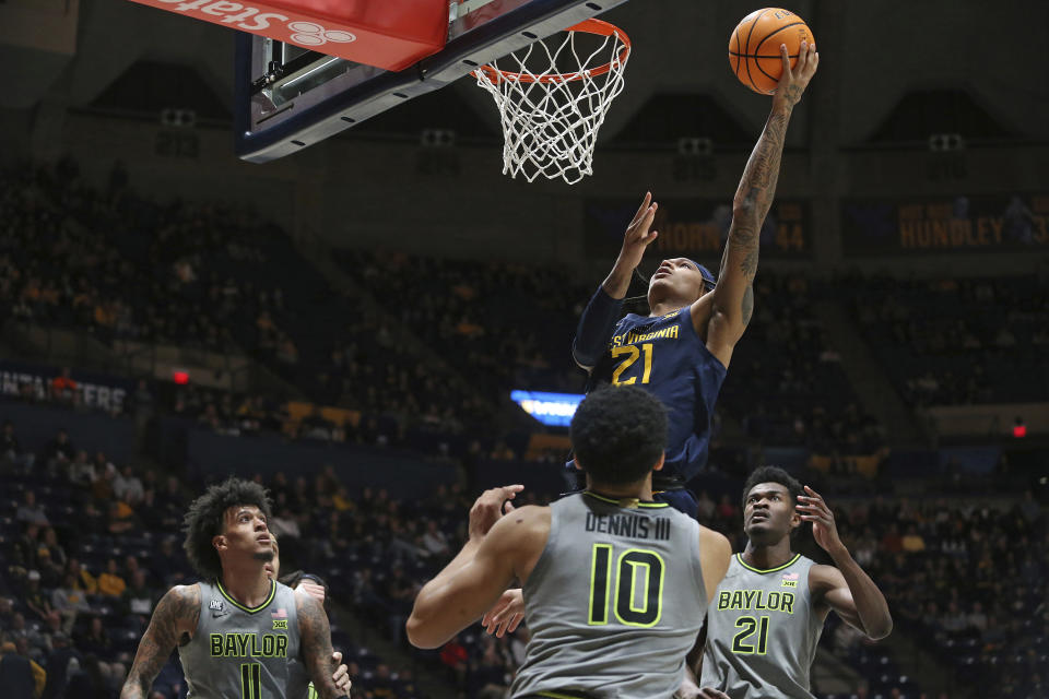 West Virginia guard RaeQuan Battle (21) shoots while defended by Baylor guard RayJ Dennis (10) and center Yves Missi (21) during the second half of an NCAA college basketball game Saturday, Feb. 17, 2024, in Morgantown, W.Va. (AP Photo/Kathleen Batten)
