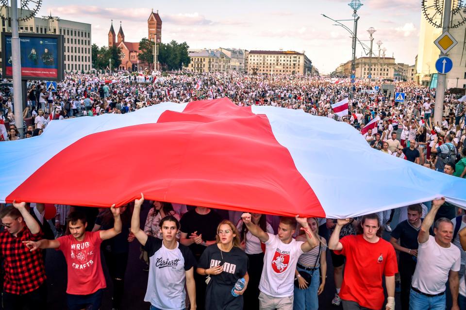 Protesters hold a giant former white-red-white flag of Belarus used in opposition to the government in central Minsk on Aug. 16, 2020.