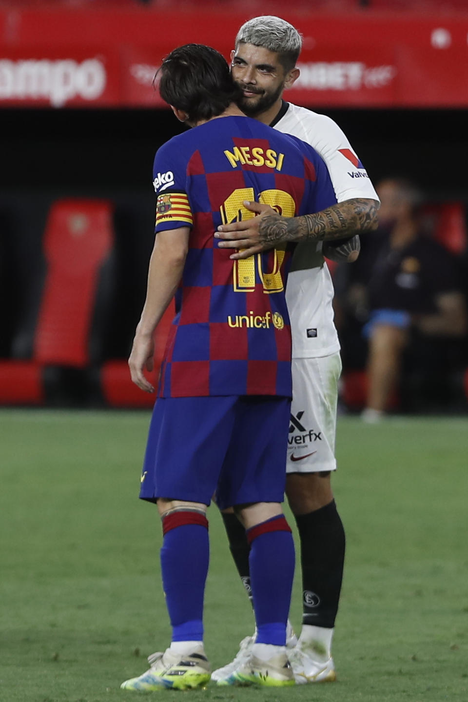 El argentino Lionel Messi, del Barcelona, abraza a su compatriota Ever Banega, del Sevilla, durante un encuentro de La Liga española, disputado el viernes 19 de junio de 2020 (AP Foto/Ángel Fernández)